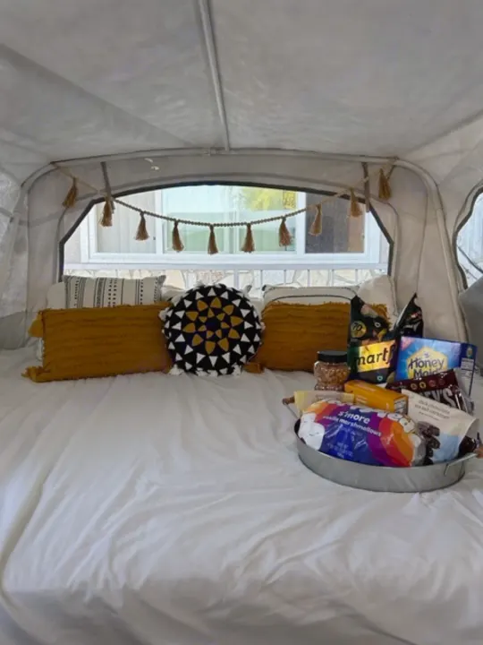 Experience a luxurious RV rental stay! This cozy interior features a plush bed, stylish pillows, and a tray of delicious s'mores.. Coleman Frontier 1993