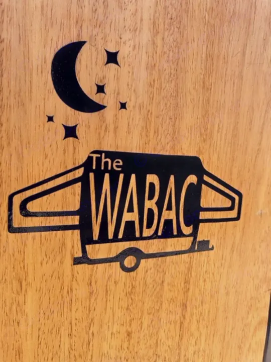 Black 'The WABAC' RV rental logo on wood, shaped like a camper van with moon and stars, hinting at night adventures.. Coleman Frontier 1993