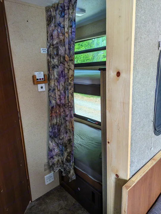 RV rental interior with bunk beds, a vibrant privacy curtain, window view, and wall-mounted controls.. Coachmen Freedom Express 2015