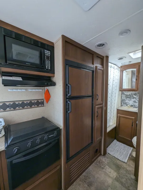 Explore the functional kitchen with microwave, stove, and fridge, and a well-equipped bathroom inside this RV rental.. Coachmen Freedom Express 2015