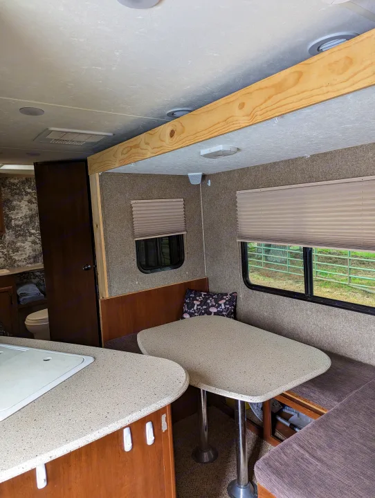 Inside an **rv rental**: a cozy dining booth, kitchen counter, and bathroom entry. Features neutral tones and functional space.. Coachmen Freedom Express 2015