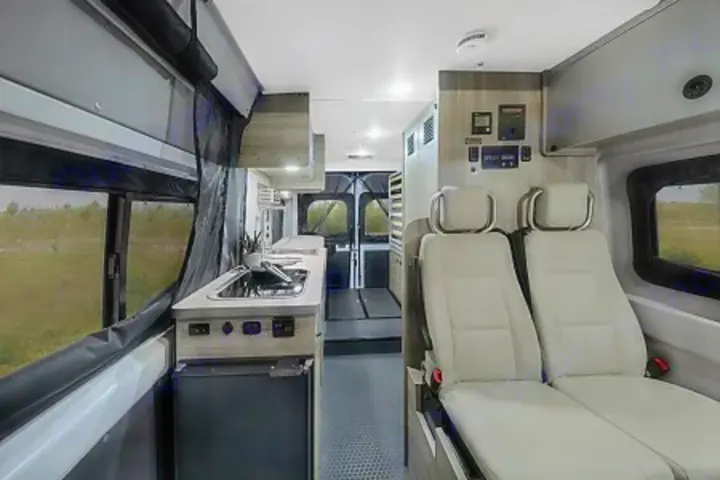 Explore this spacious RV rental interior, featuring a well-equipped kitchen, versatile seating, and scenic window views.. Winnebago Solis PX 2024