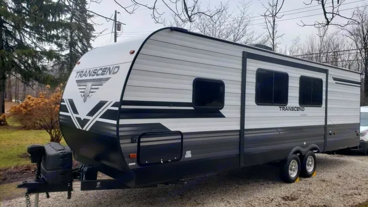 RV rental: A grey and black Transcend travel trailer with dual axles, parked on a gravel driveway outdoors.. Grand Design Transcend 2019