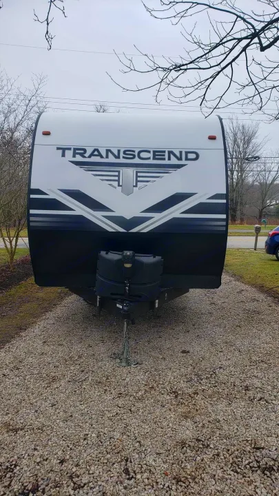 This front view of a Transcend travel trailer, perfect for your next RV rental adventure, is parked on a gravel driveway.. Grand Design Transcend 2019