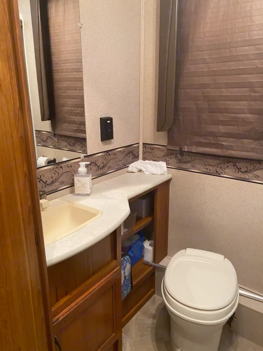 RV rental bathroom with a compact sink, countertop, toilet, mirror, and storage, showcasing its amenities.. Jayco Redhawk 2016