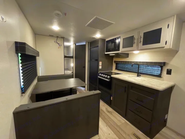 RV rental interior featuring a modern kitchen with sink and stove, dinette seating, and bunk beds visible in the back.. KZ Sportsmen SE 260BHSE 2022