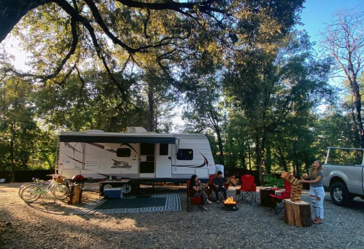 An RV rental for outdoor recreation: friends by campfire, playing Jenga at a tree-shaded campsite.. Jayco Jay Flight 2015