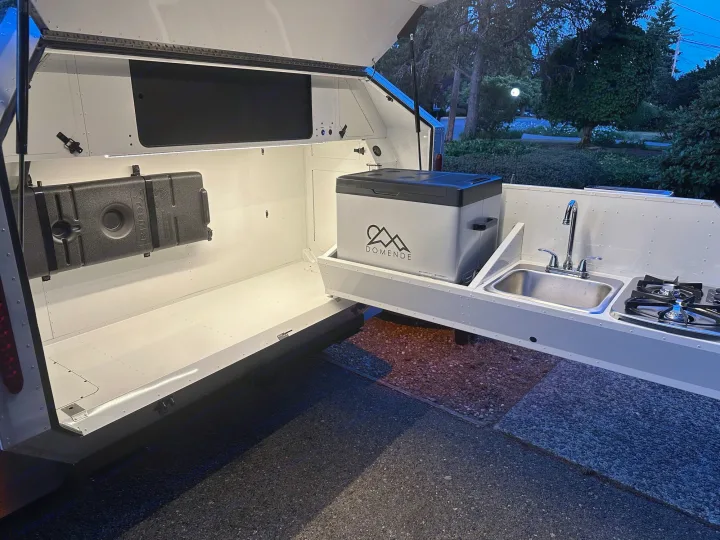 Brightly lit rv rental camper with an extended outdoor kitchen: cooler, sink, and stove ready for adventure cooking.. Mammoth Overland Mammoth HV 2023
