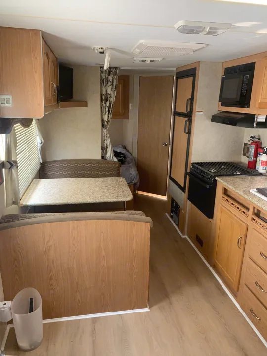 RV rental interior: well-equipped kitchen, dining booth, and bunk area. Light wood finishes create a spacious feel.. Fleetwood Mallard 2008