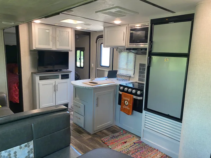 Modern RV rental interior with kitchen, living area, and a glimpse into the bedroom.. Keystone RV Bullet Ultra Lite 2019