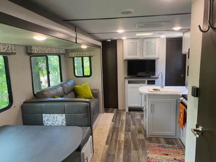 Spacious rv rental interior showing living area with sofa, dinette, and modern kitchenette. Bright, comfortable travel space.. Keystone RV Bullet Ultra Lite 2019
