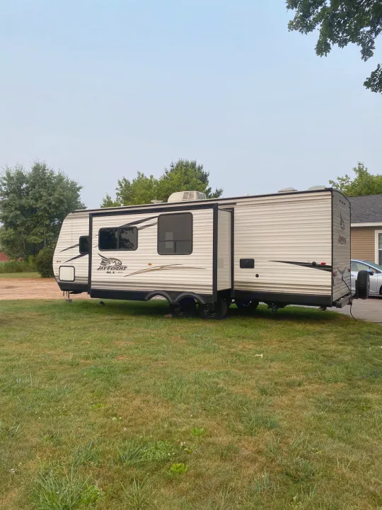 White Jay Flight travel trailer with slide-out extended, parked on a grassy lawn. Perfect for an rv rental vacation.. Jayco Jay Flight SLX 2017