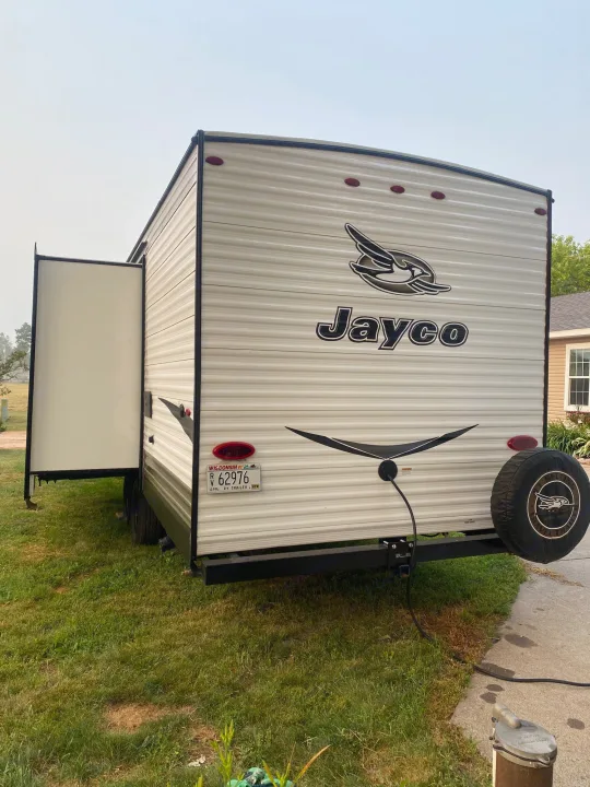 White Jayco RV rental with slide-out open, parked on grass. Wisconsin plate visible.. Jayco Jay Flight SLX 2017