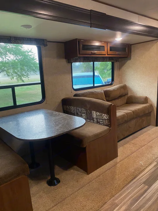 Cozy RV rental interior with a dining booth, sofa, overhead storage, and large windows revealing a scenic view.. Jayco Jay Flight SLX 2017