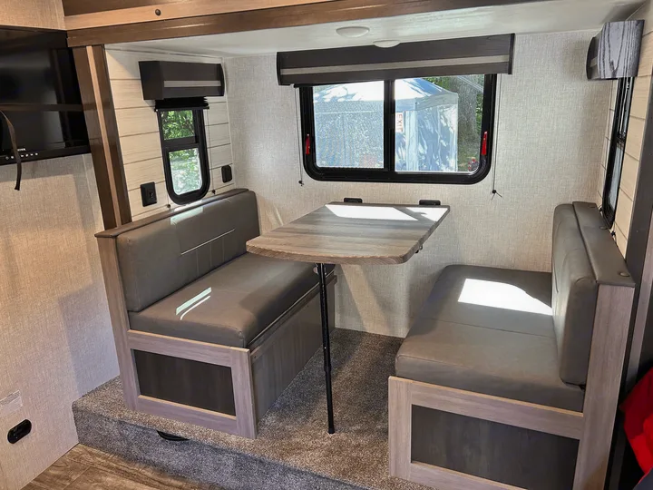 Cozy RV rental interior featuring a practical dinette with two cushioned benches, a table, and windows. Great for travel adventures.. Sunset Trail 188BH 2022