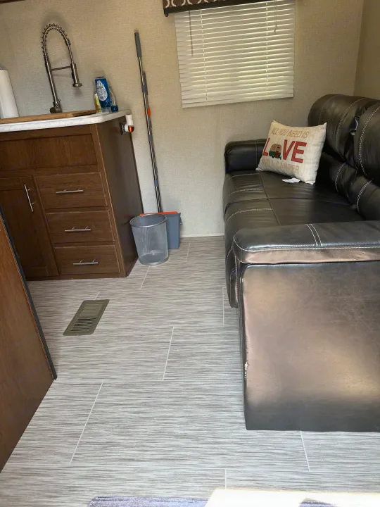 Inside this RV rental: a modern kitchen with a large sink, dark cabinets, a black leather sofa, and textured gray flooring.. Avenger ATI 2018