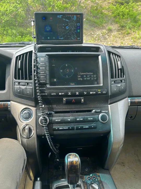 Inside an RV rental: a dusty dashboard shows GPS navigation at 61°N, 149°W, plus a tablet playing a history podcast.. Toyota Land Cruiser 2008