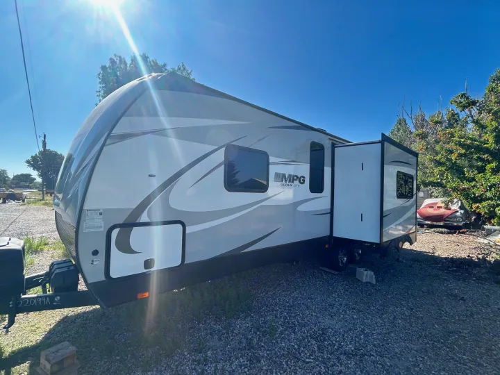 Bright, sunny day view of a white & grey MPG Ultra-Lite travel trailer with its slide-out extended. Great for RV rental!. Cruiser Rv Corp 2450RK 2019