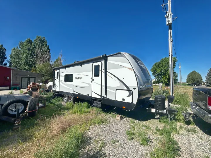 A clean, modern travel trailer, great for an RV rental, parked under a bright blue sky amidst green foliage.. Cruiser Rv Corp 2450RK 2019