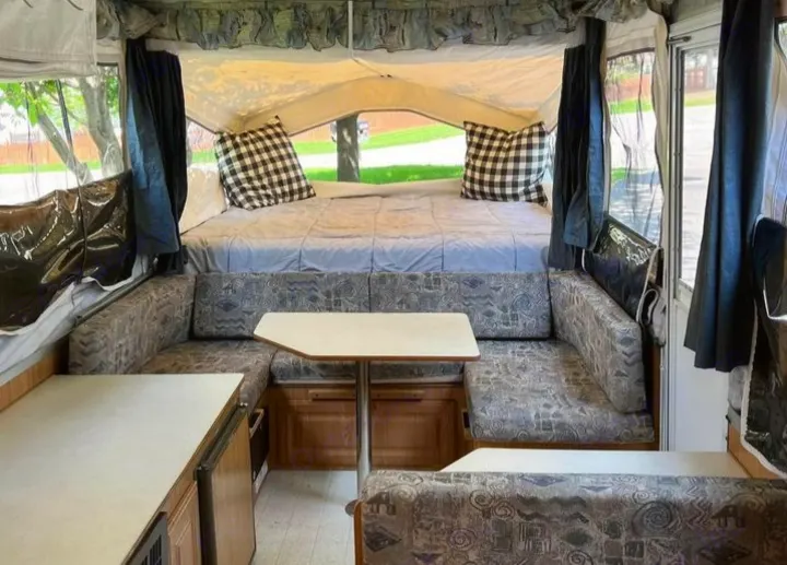 Pop-up RV rental interior: A comfortable bed, U-shaped dinette, and compact kitchenette for your adventures.. Forest River Rockwood Premier 2004