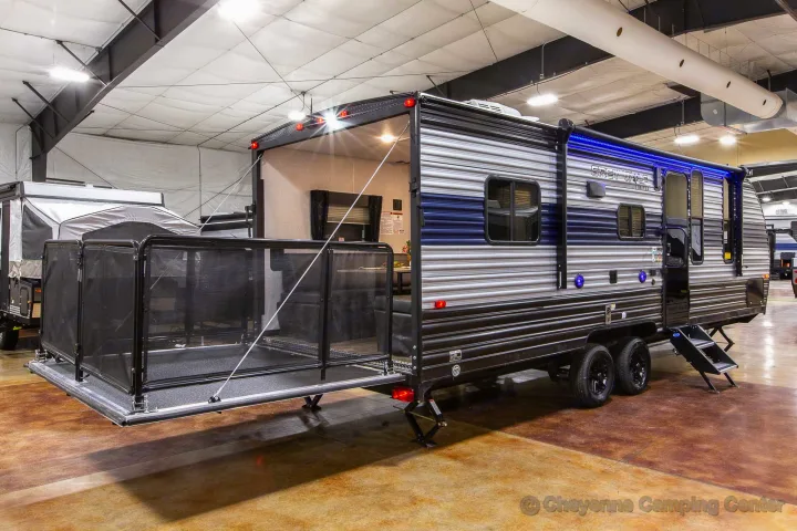 A blue and grey striped toy hauler travel trailer with a lowered rear deck, ready for RV rental adventures.. Forest River Wolf Pup 2021