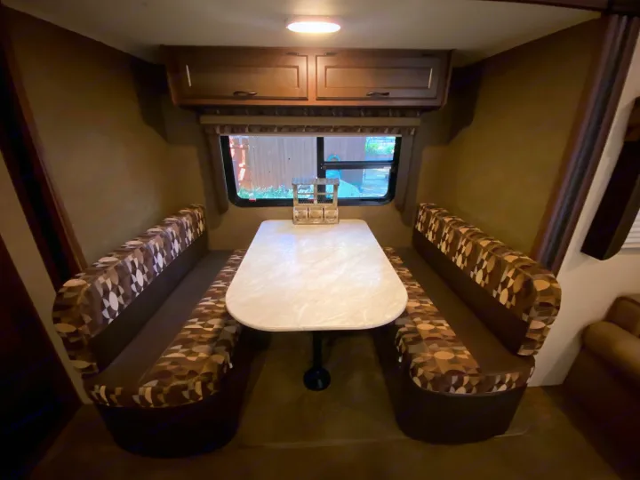 RV rental dinette with booth seating and a white table. Enjoy comfortable dining and views from the window.. Jayco Jay Flight 2015