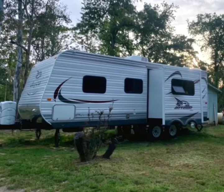 This Jay Flight travel trailer RV rental, parked amidst trees, offers a comfortable camping experience.. Jayco Jay Flight 2015
