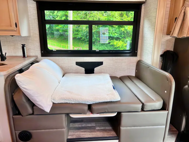 RV rental dinette easily converts to a cozy bed, featuring a scenic window, pop-up outlet & plush seating.. Jayco Redhawk 31F 2024