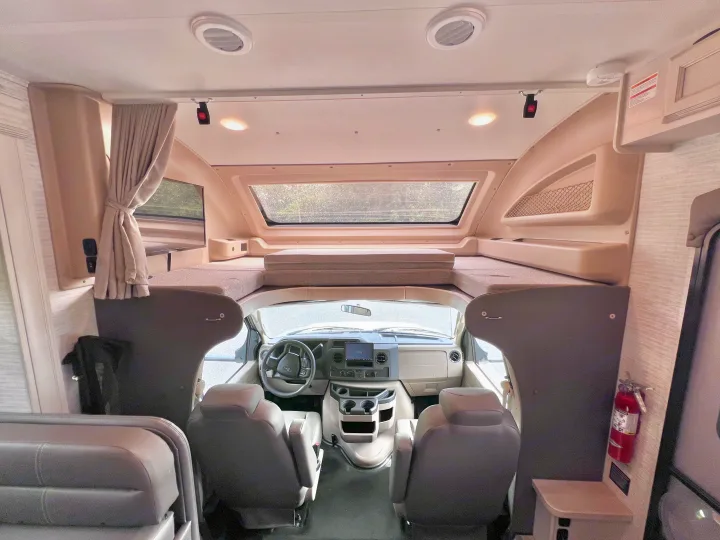 Inside this spacious RV rental, a bright cockpit with a steering wheel and dashboard leads to a large cab-over bed.. Jayco Redhawk 31F 2024