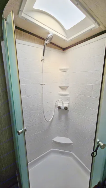 Clean RV rental shower with skylight, white textured walls, and clear glass door, seen from above.. Cruiser RV Shadow Cruiser 2019