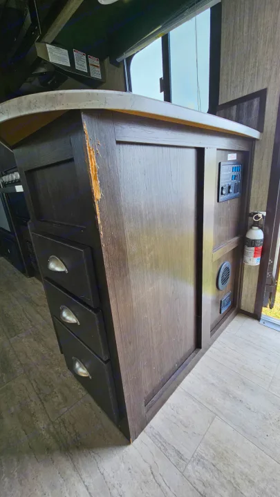 RV rental interior showing a damaged counter, control panel, fire extinguisher, and storage drawers.. Cruiser RV Shadow Cruiser 2019