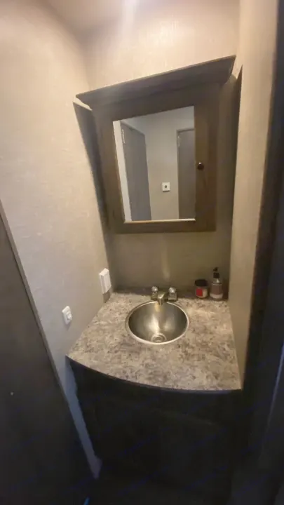 RV rental bathroom featuring a compact vanity with a metal sink, faucet, mirror, and speckled counter.. Eclipse Recreational Vehicles Attitude 2016