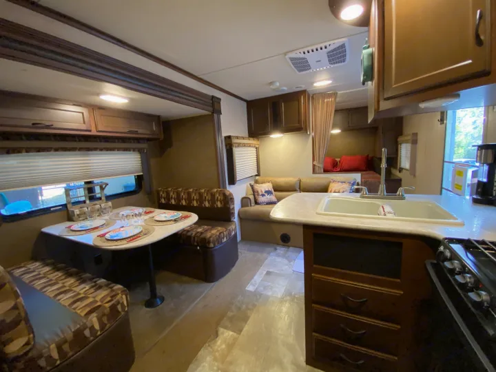 RV rental: Bright, modern interior with kitchen sink/stove, dining booth, and a cozy living area with sofa and bunk bed.. Jayco Jay Flight 2015