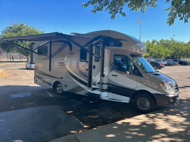 A modern Citation rv rental with an extended awning parked in a sunny lot, ready for travel or camping.. Thor Citation 2015
