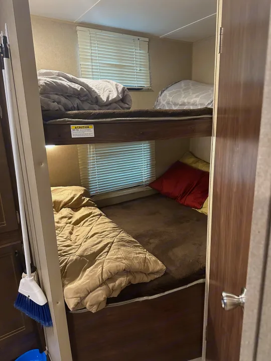 Experience an RV rental with practical bunk beds. Upper and lower bunks, cozy bedding, and windows offer comfortable stays.. Coachmen 264bh 2017