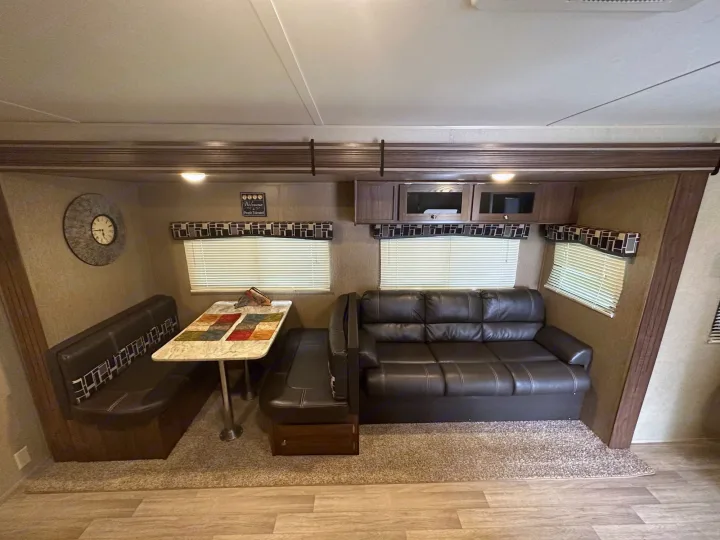 RV rental interior: spacious living area with a dinette, comfy sofa, and overhead storage. Clean, modern design.. Coachmen 264bh 2017
