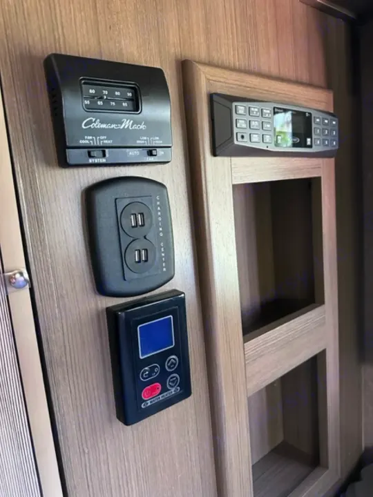 RV rental controls: Coleman-Mach thermostat, USB ports, system monitor, and remote control in a modern interior.. Thor Vegas 2018