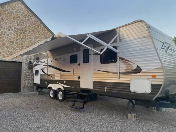 This Zinger travel trailer, perfect for an RV rental adventure, is parked with its awning extended for shade.. Crossroads RV Zinger 2014