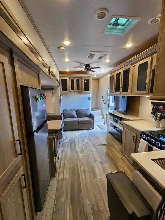Bright, modern RV rental interior. View of kitchen, living space, and rear garage area with sofa.. Forest River Flagstaff Super Lite 2022