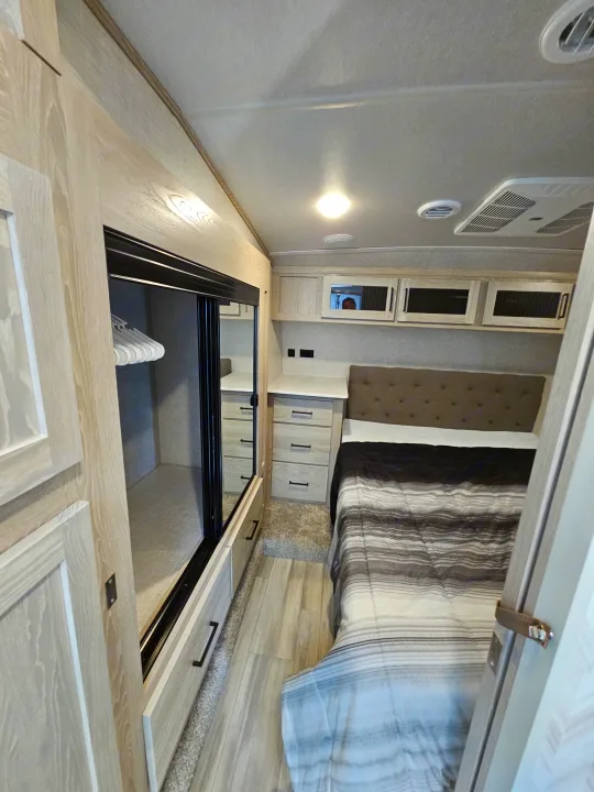 RV rental bedroom interior, showcasing a bed, nightstands, and ample built-in floor storage with hangers.. Forest River Flagstaff Super Lite 2022