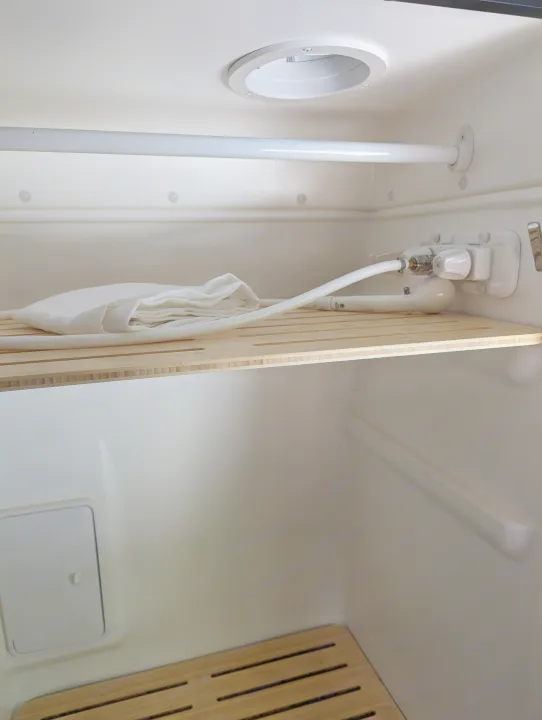 rv rental compact wet bath interior, showing shower controls, hose, white towel, and slatted wooden shelf.. Winnebago Revel 2023