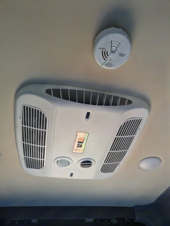 RV rental ceiling: an air conditioning unit, carbon monoxide alarm, and lights for safety and comfort inside.. Winnebago Revel 2023