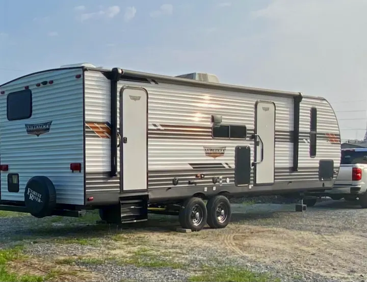 A large Forest River Wildwood travel trailer, perfect for rv rental, parked on a sunny day.. Forest River Wildwood 2021