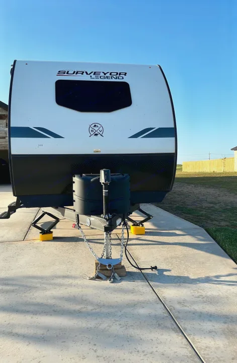 Front view of a white & black Surveyor Legend travel trailer, parked with leveling blocks, ready for rent.. Forest River Surveyor Legend 2022