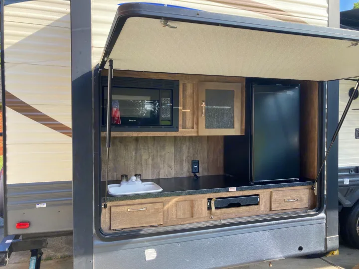 This RV rental offers an outdoor kitchen: microwave, fridge, sink, pull-out cooktop, and storage drawers.. Palomino Puma 31DBTS 2020