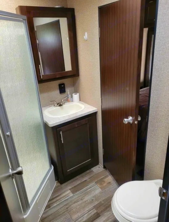 Cozy RV rental bathroom with glass shower, sink vanity, toilet, and mirrored cabinet, all optimized for compact living.. Forest River Wolf Pack 2016