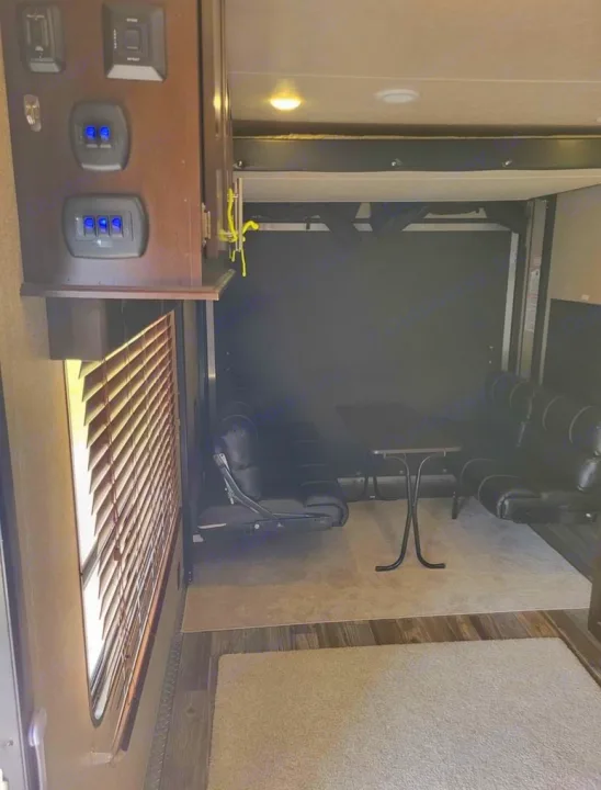 Spacious RV rental interior with convertible seating, a table, and overhead bunk. Versatile living/garage space.. Forest River Wolf Pack 2016