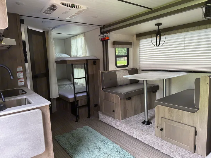 Cozy rv rental interior featuring a kitchenette, bunk beds, and dinette area for comfortable travels.. Forest River Surveyor Legend 2021