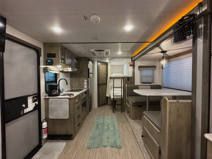 Spacious, modern RV rental interior featuring kitchen, dinette, and bunk beds. Perfect for family adventures.. Forest River Surveyor Legend 2021