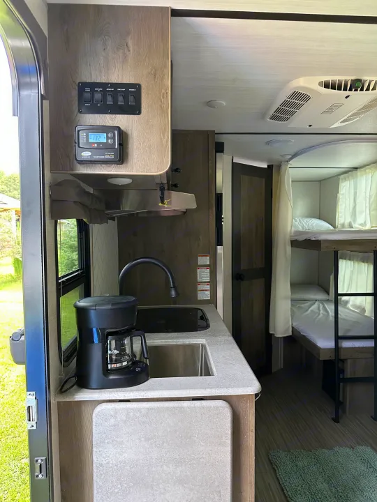 RV rental interior: Kitchenette, Mr. Coffee maker, solar panel display, and bunk beds are visible.. Forest River Surveyor Legend 2021